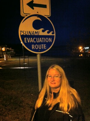 Woman standing in front of a tsunami evacuation zone sign.