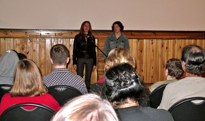 Two people talking into the microphone and giving a presentation in the hall