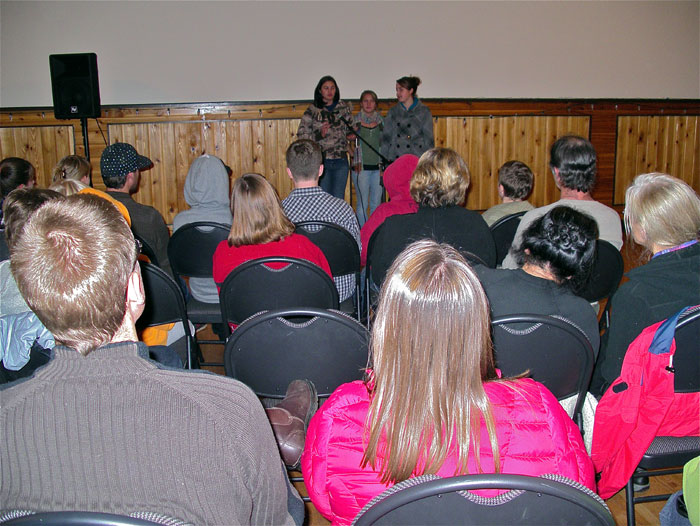 Three girls talking into the microphone and giving a presentation in the hall