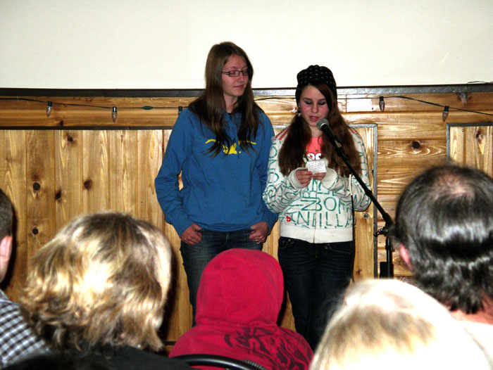 Two girls talking into the microphone and giving a presentation in the hall