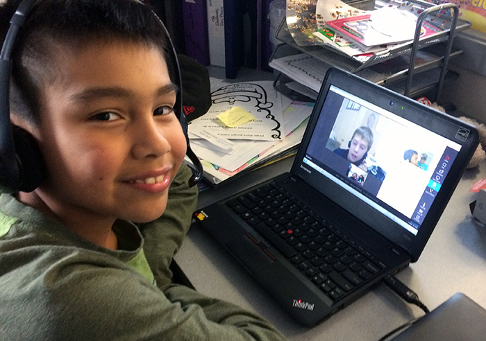 Boy smiling in front of a laptop.