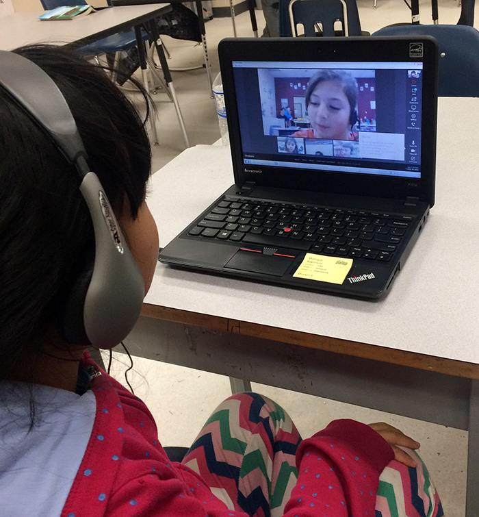 Child wearing headphones and looking at a laptop screen.