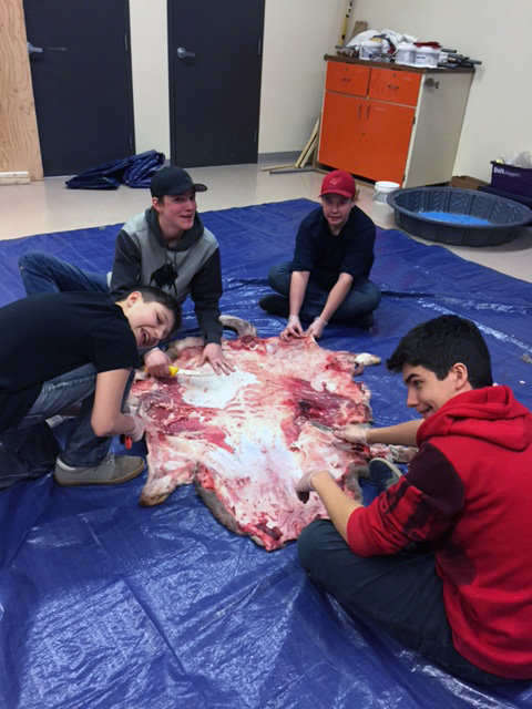 4 boys working on the deerskin 