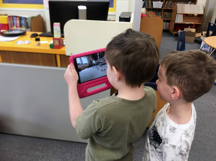 Two young boys looking into an iPad screen. 