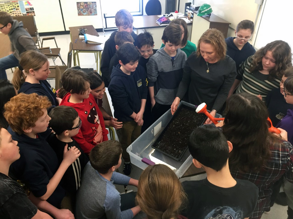 Students observing a teacher with the soil