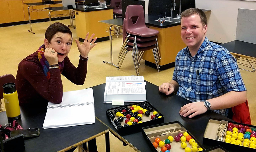 Two people sitting at a table and working together.