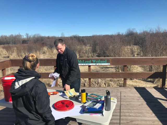 Two people sitting outside at a table and working together